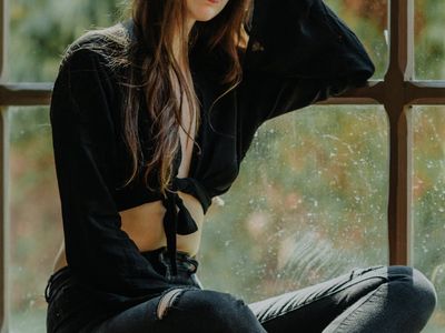 A person in a relaxed pose looking out a window.